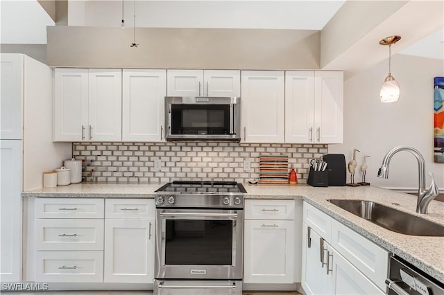 kitchen with sink, hanging light fixtures, light stone countertops, stainless steel appliances, and white cabinets