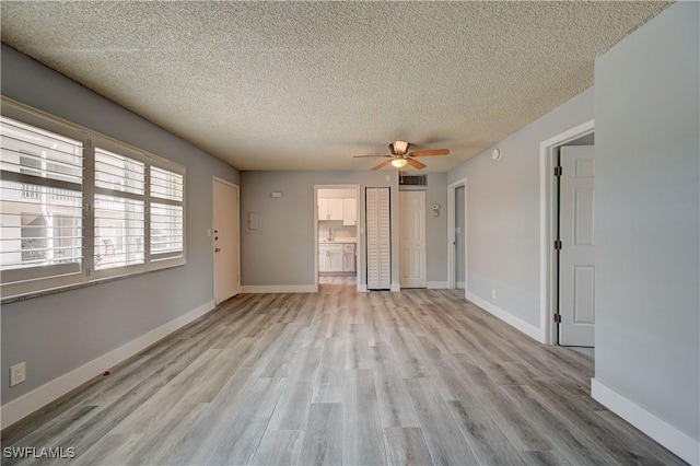 interior space with ceiling fan, light wood-type flooring, and a textured ceiling