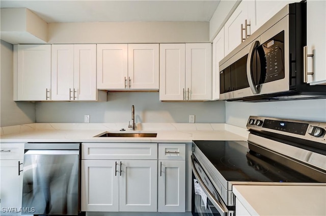 kitchen featuring sink, light stone countertops, white cabinets, and appliances with stainless steel finishes