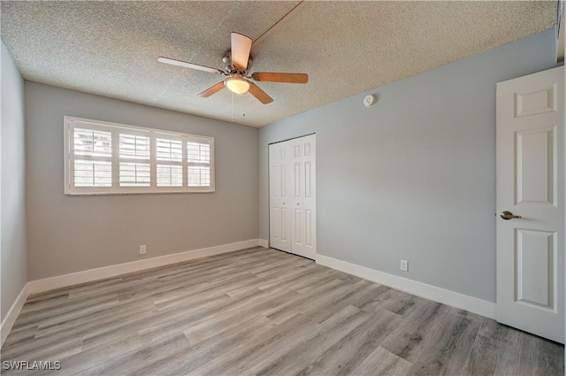 unfurnished bedroom with light hardwood / wood-style floors, a textured ceiling, ceiling fan, and a closet