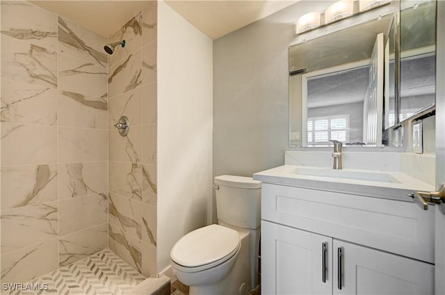 bathroom featuring vanity, toilet, and tiled shower