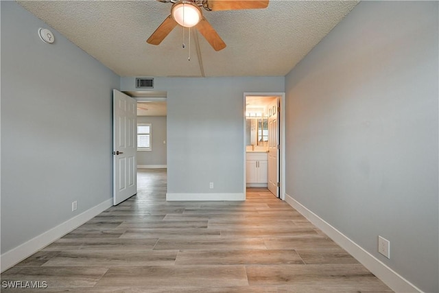 unfurnished bedroom with a textured ceiling, light wood-type flooring, ceiling fan, and ensuite bathroom