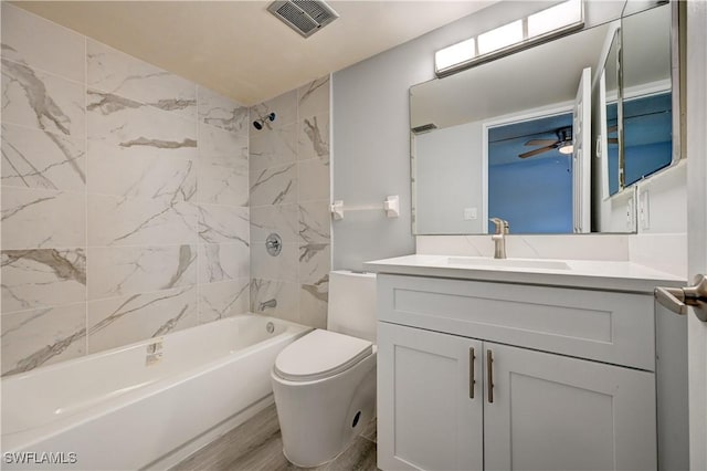 full bathroom featuring hardwood / wood-style flooring, tiled shower / bath, vanity, and toilet