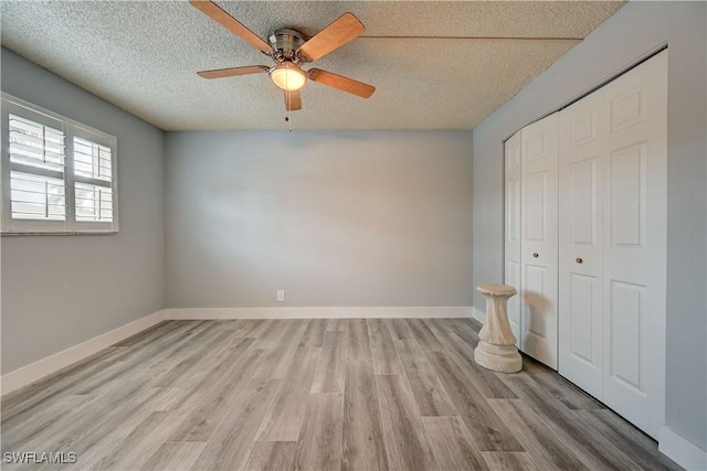 unfurnished bedroom featuring light hardwood / wood-style floors, a textured ceiling, ceiling fan, and a closet