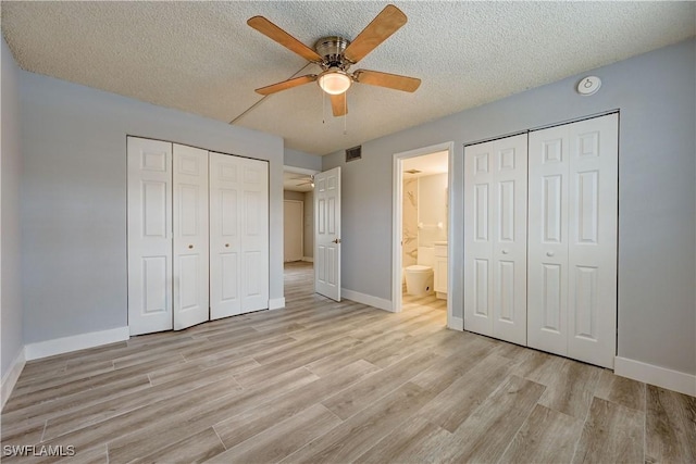 unfurnished bedroom featuring multiple closets, ceiling fan, ensuite bath, and a textured ceiling