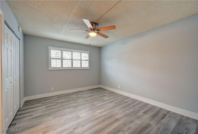 unfurnished bedroom featuring ceiling fan, light wood-type flooring, a closet, and a textured ceiling