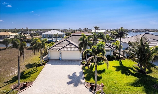 view of front of property with decorative driveway, a tile roof, an attached garage, a front yard, and a residential view