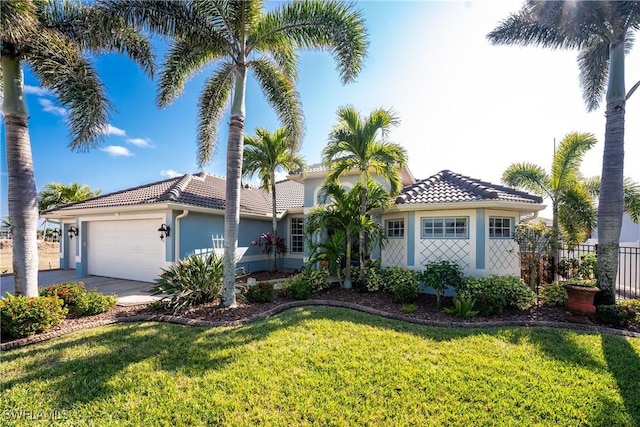 view of front of home featuring a tile roof, stucco siding, a front yard, fence, and a garage