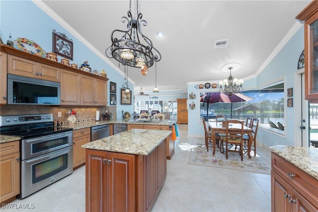 kitchen with light stone countertops, hanging light fixtures, crown molding, and stainless steel appliances