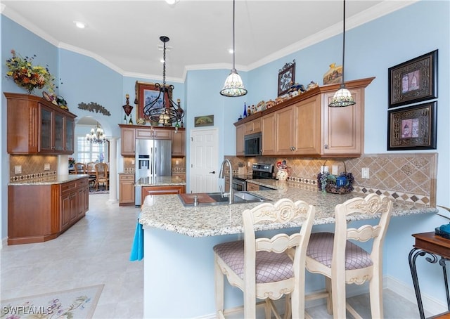 kitchen featuring arched walkways, crown molding, appliances with stainless steel finishes, a peninsula, and a kitchen breakfast bar