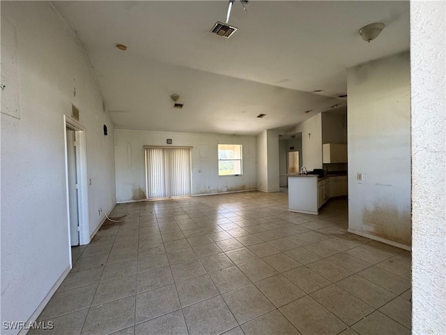 unfurnished living room featuring visible vents, vaulted ceiling, baseboards, and light tile patterned floors