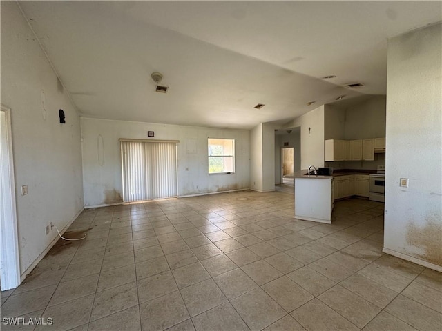 interior space featuring white electric stove, light tile patterned floors, dark countertops, open floor plan, and vaulted ceiling