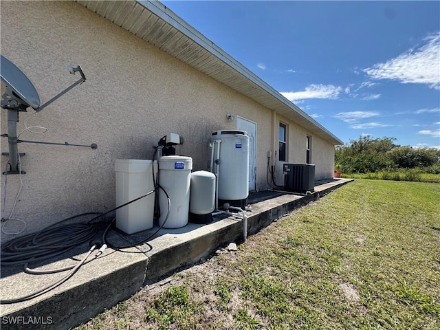 view of side of home featuring central AC unit, a lawn, and stucco siding