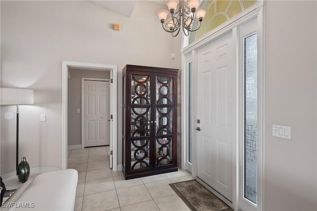 entryway featuring light tile patterned floors, a towering ceiling, and a chandelier