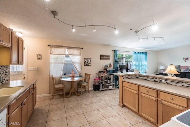 kitchen featuring sink, backsplash, light tile patterned flooring, and dishwasher