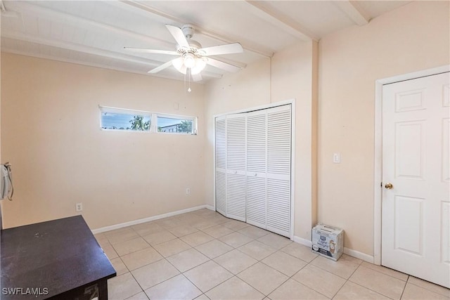 unfurnished bedroom with a closet, beamed ceiling, light tile patterned flooring, and ceiling fan