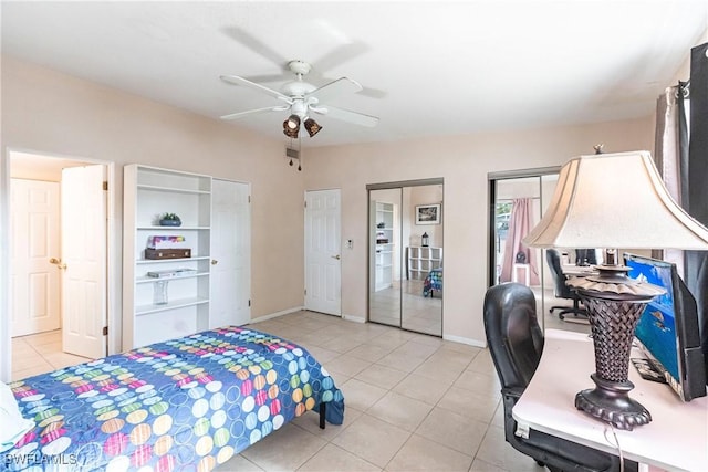 tiled bedroom featuring ceiling fan and multiple closets