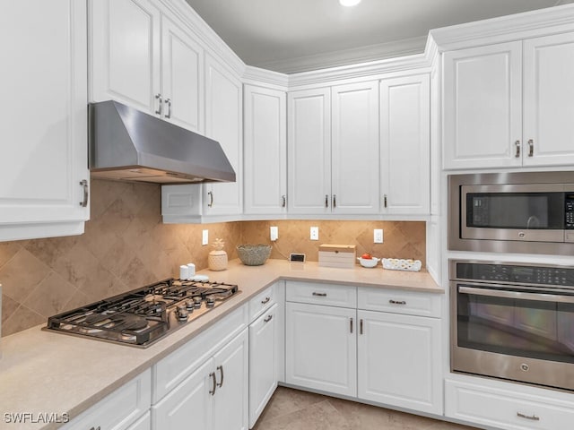 kitchen with appliances with stainless steel finishes, light tile patterned floors, white cabinets, and decorative backsplash