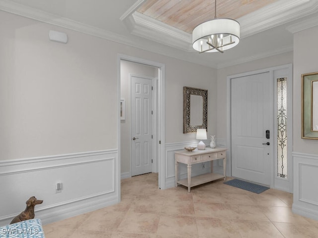 tiled foyer with ornamental molding and a chandelier