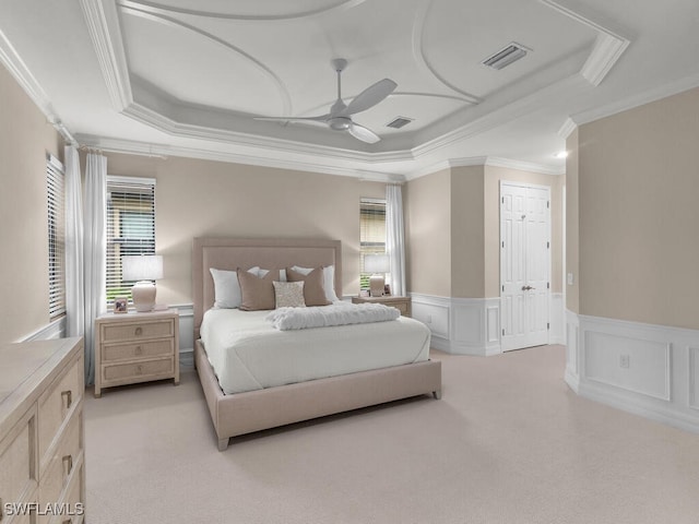 bedroom featuring light carpet, crown molding, a raised ceiling, and ceiling fan