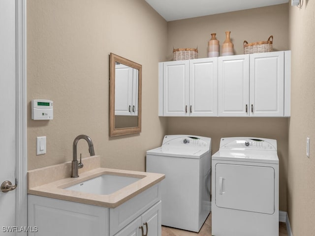 clothes washing area featuring cabinets, sink, and washing machine and clothes dryer