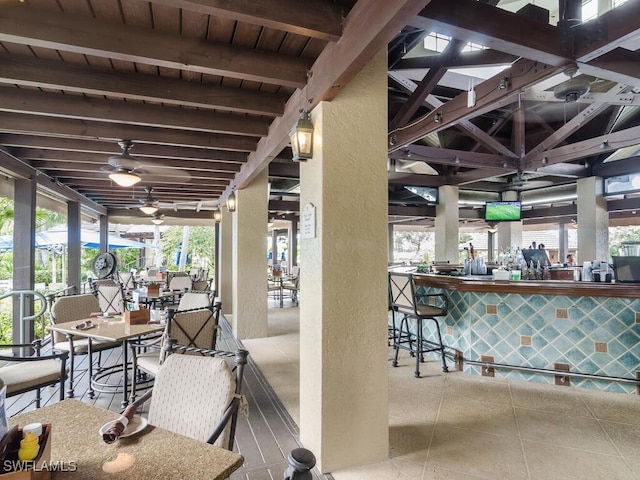 view of patio with ceiling fan and a bar