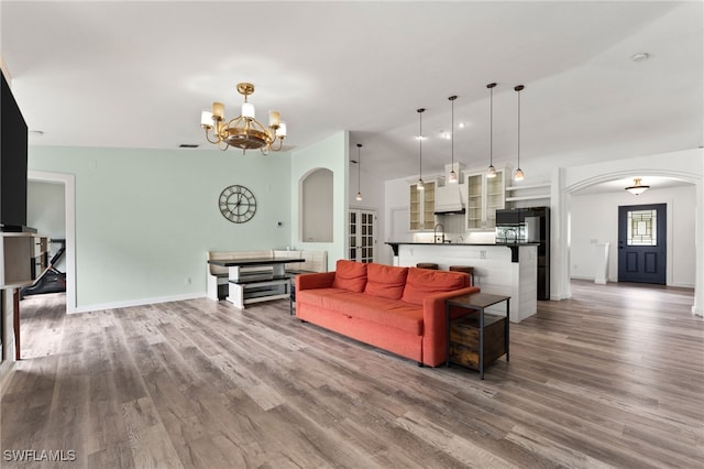 living room with sink, light wood-type flooring, lofted ceiling, and an inviting chandelier