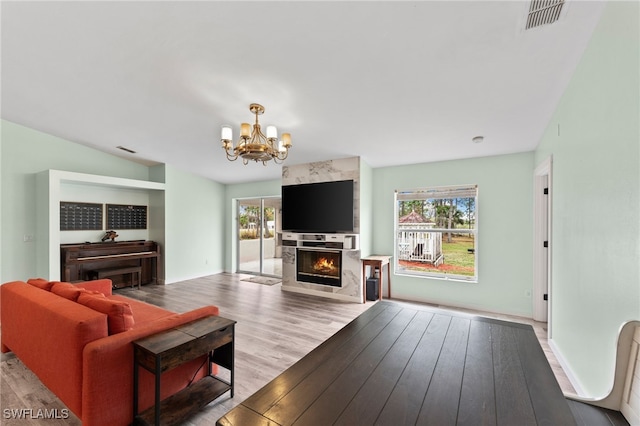 living room featuring a chandelier, a large fireplace, hardwood / wood-style floors, and a healthy amount of sunlight