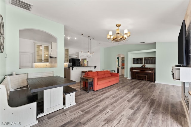 living room featuring an inviting chandelier, lofted ceiling, and wood-type flooring