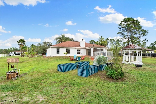 back of property with a gazebo, a lawn, and a sunroom