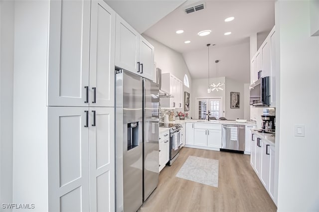 kitchen with light hardwood / wood-style floors, pendant lighting, appliances with stainless steel finishes, white cabinets, and a chandelier