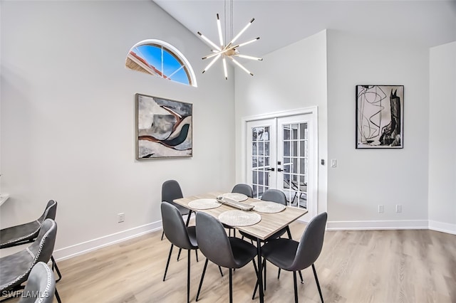 dining area featuring high vaulted ceiling, french doors, light wood-type flooring, and a chandelier