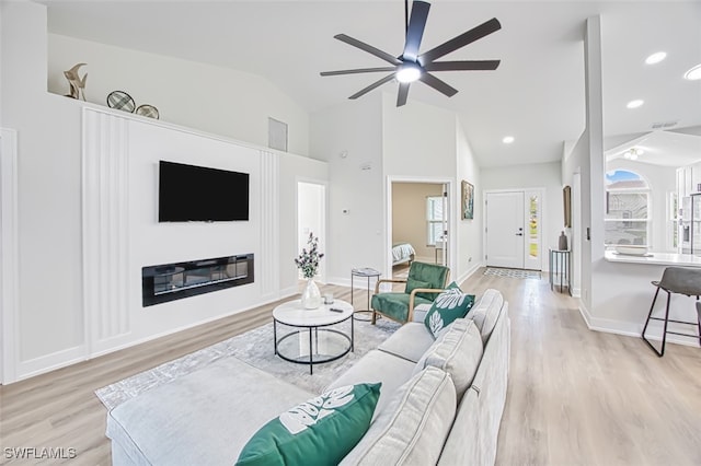 living room featuring ceiling fan, lofted ceiling, and light hardwood / wood-style floors