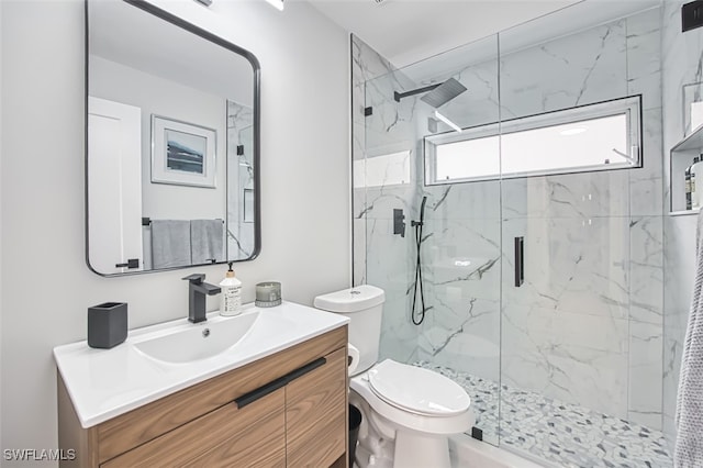 bathroom featuring toilet, vanity, and a shower with shower door