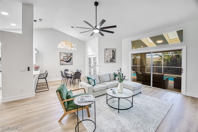 living room with lofted ceiling, ceiling fan with notable chandelier, and light hardwood / wood-style floors