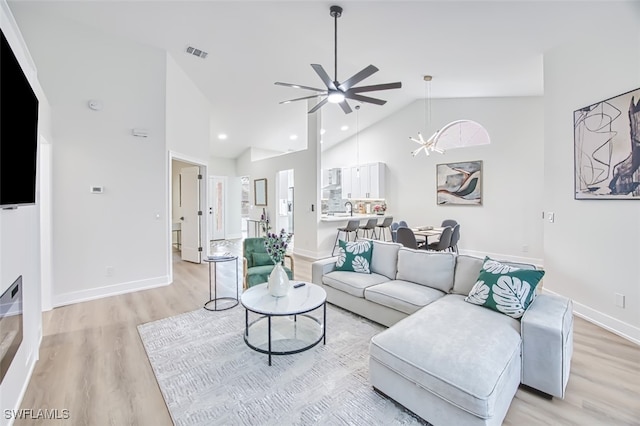 living room featuring high vaulted ceiling, sink, ceiling fan with notable chandelier, and light hardwood / wood-style flooring