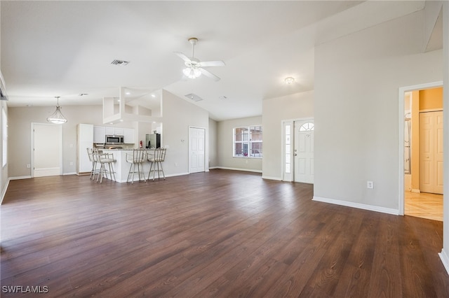 unfurnished living room featuring vaulted ceiling, dark wood-style flooring, a ceiling fan, and baseboards