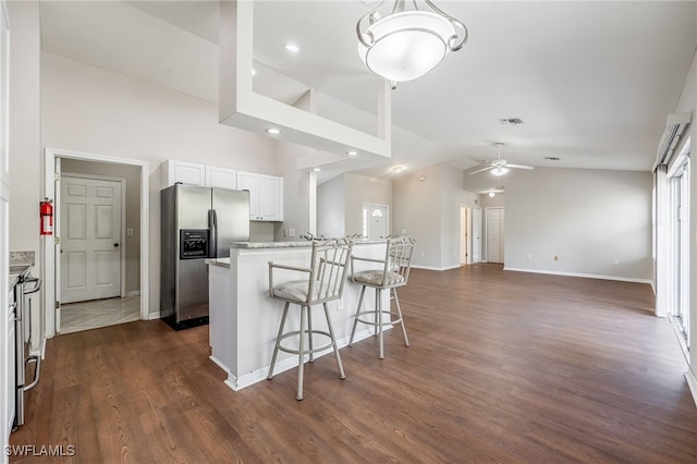 kitchen with a breakfast bar area, white cabinets, light countertops, dark wood-style floors, and stainless steel fridge