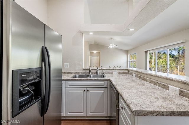 kitchen with a sink, a peninsula, stainless steel refrigerator with ice dispenser, and light countertops