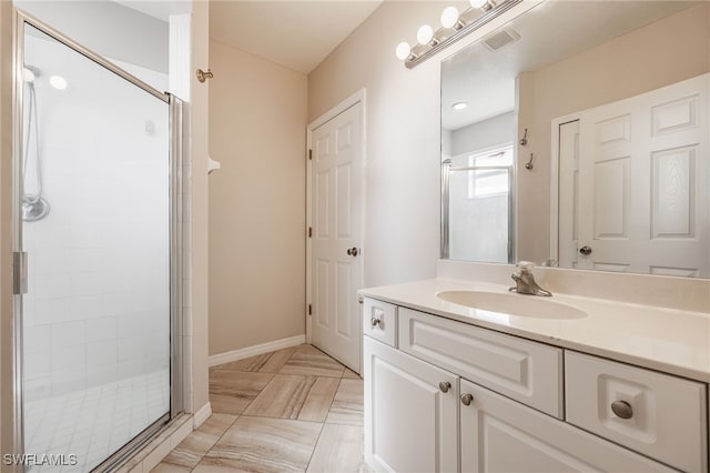 full bath featuring vanity, a shower stall, visible vents, and baseboards