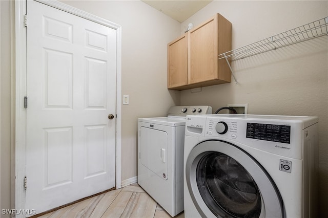 washroom with baseboards, cabinet space, and washing machine and clothes dryer