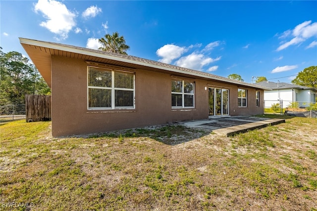 back of property with fence, a lawn, and stucco siding