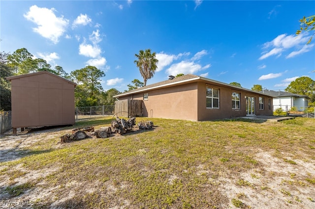 exterior space with an outdoor structure, fence, a lawn, stucco siding, and a storage unit