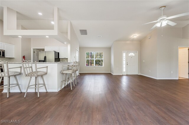 kitchen featuring ceiling fan, stainless steel appliances, high vaulted ceiling, white cabinets, and a breakfast bar