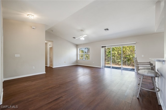 unfurnished living room featuring baseboards, visible vents, a ceiling fan, dark wood-style flooring, and vaulted ceiling