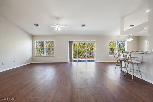 unfurnished living room with a wealth of natural light, dark wood finished floors, and visible vents