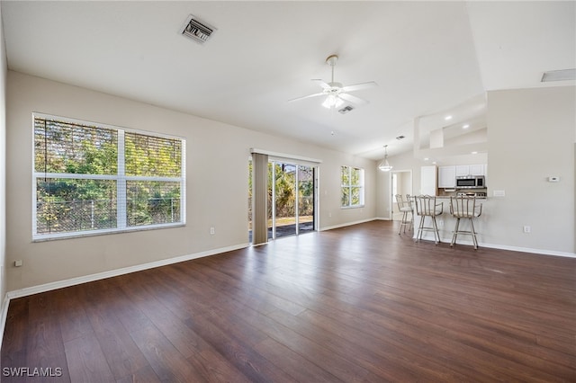 unfurnished living room featuring lofted ceiling, ceiling fan, dark wood-style flooring, visible vents, and baseboards