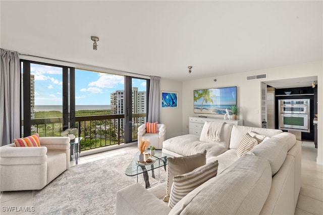 living area featuring visible vents, light tile patterned floors, a wall of windows, and a water view