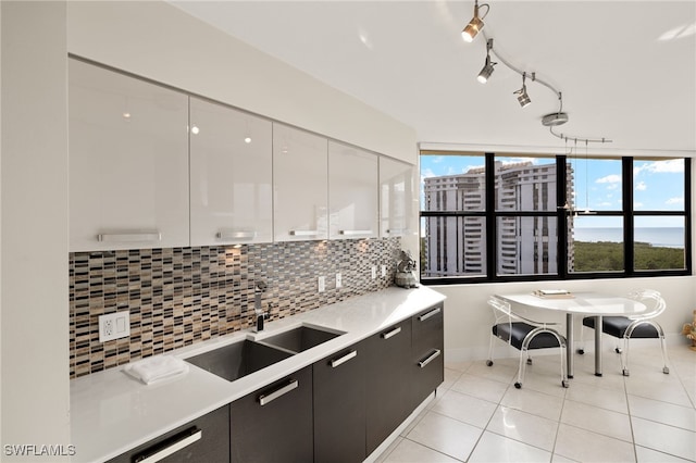 kitchen with sink, light tile patterned flooring, white cabinetry, and backsplash