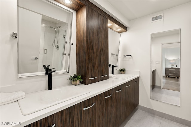 bathroom with vanity, a tile shower, and tile patterned floors